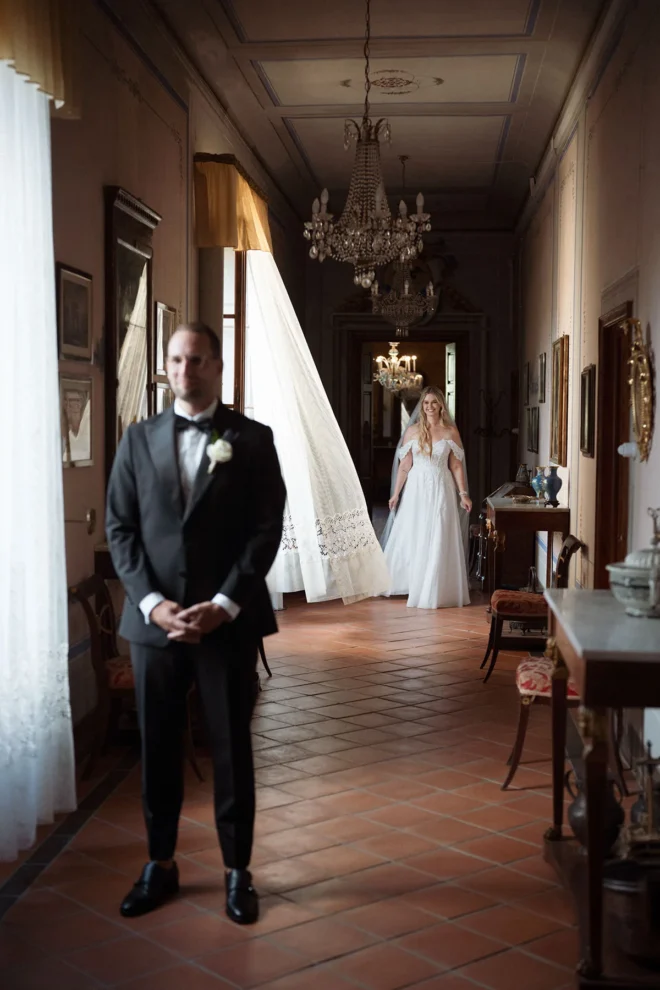 Emotional first look between the bride and groom in the majestic interiors of Borgo Castelvecchi.