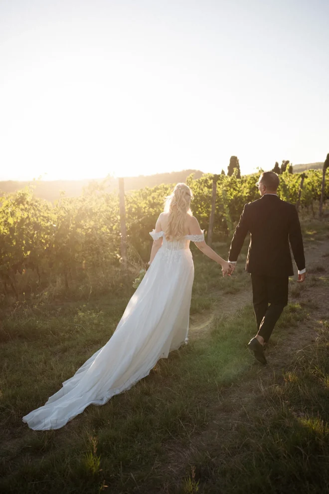 A beautiful couple walking through the vineyards at Borgo Castelvecchi during golden hour. Tuscany wedding photographer.